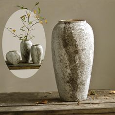 a vase sitting on top of a wooden table next to three vases with flowers in them