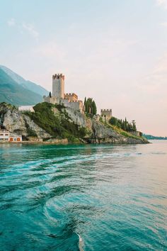 an island in the middle of water with a castle on it's cliff side