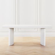 a white bench sitting on top of a hard wood floor next to a white wall