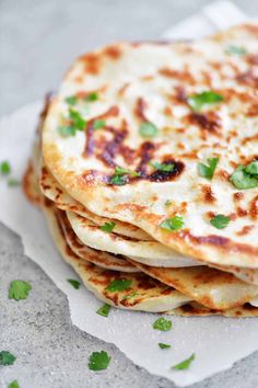 several flatbreads stacked on top of each other with green garnishes