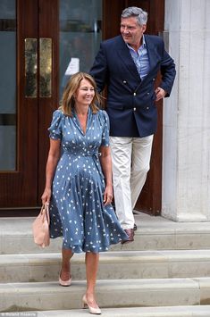 a man and woman are walking down the steps together, one is wearing a blue dress with white polka dots