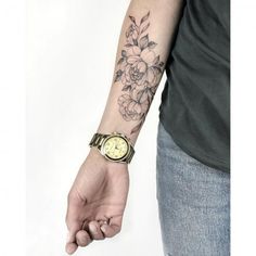 a person with a wrist tattoo holding onto a watch