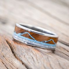 a wedding band with blue and brown wood inlays on an old wooden surface