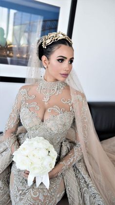 a woman in a wedding dress with a veil on her head and flowers in her hand