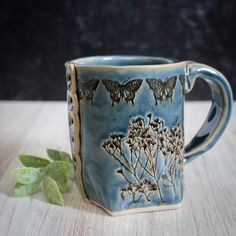 a blue mug with butterflies on it sitting on a table