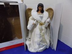 an angel figurine sitting on top of a white chair next to a box