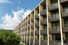 an apartment building with balconies and balconyes on the second floor, under a partly cloudy blue sky