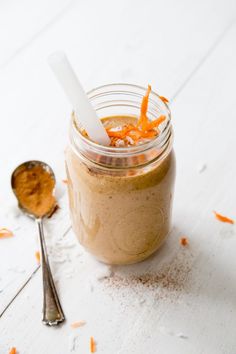 a jar filled with food sitting on top of a white table next to a spoon