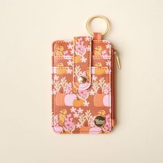 an orange and pink flowered wallet with a gold keychain hanging from it