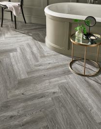 a bathroom with grey wood flooring and a bathtub in the corner next to it