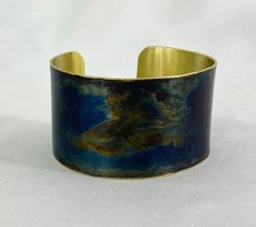 These unique, hand-formed copper and brass cuff bracelets with vibrant patinas create stunning accents to your personal style. Dress up or down- either way you'll be wearing an adornment that will turn heads, start conversations, and delight the eye of the beholder. This is a customizable brass cuff with a beautiful Torch Blue patina. Choose widths of 1-3/4"-2". Sizes: Small= 6-6-3/8", Medium: 6.5-6-3/4", Large=7-7.5". Use a fabric tape to measure the circumference of your wrist to judge your si Artisan Blue Cuff Bracelet, Adjustable Blue Cuff Bracelet With Patina, Adjustable Blue Patina Cuff Bracelet, Brass Cuff Bracelet With Patina As A Gift, Blue Patina Cuff Bracelet As Gift, Blue Cuff Bracelet With Patina As A Gift, Blue Patina Cuff Bracelet As A Gift, Blue Cuff Bracelet With Patina For Gifts, Brass Cuff Bracelet