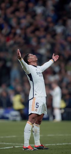 a man standing on top of a soccer field holding his arms up in the air