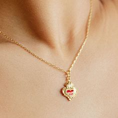 Clock up of the Sacred Heart Necklace worn around a models neck. Gold Enamel Heart Necklace For Gift, Enamel Pendant Charm Necklace With Adjustable Chain, Heart-shaped Gold Plated Charms For Gifts, Heart-shaped Enamel Charms Necklaces, Gold Enamel Heart Necklace For Valentine's Day, Heart-shaped Enamel Charms Necklace, Valentine's Day Gold Enamel Heart Necklace, Heart-shaped Gold Enamel Necklace, Gold Heart-shaped Enamel Necklace