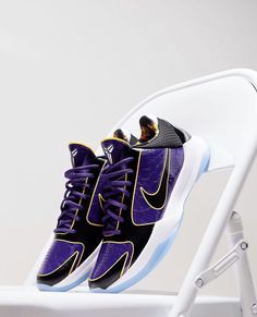 a pair of purple and black shoes sitting on top of a white chair