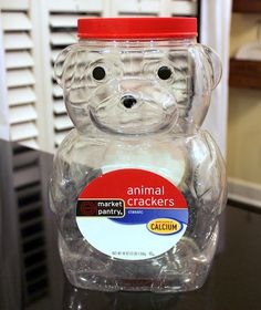 an animal cracker jar sitting on top of a black table next to a window