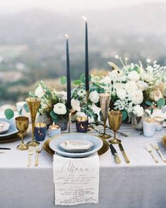 an elegant table setting with candles, flowers and napkins on top of the table