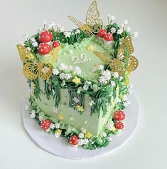 a green cake decorated with flowers and butterflies