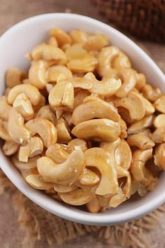 a white bowl filled with cashews on top of a wooden table