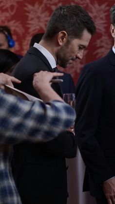 two men standing next to each other holding wine glasses