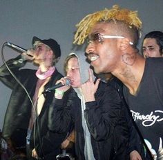 three young men singing into microphones in front of a crowd