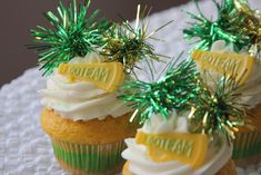 three cupcakes decorated with white frosting and green sprinkles