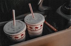 two cups with straws sitting in the center console of a car