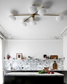 a kitchen with marble counter tops and lights above the island in front of an oven