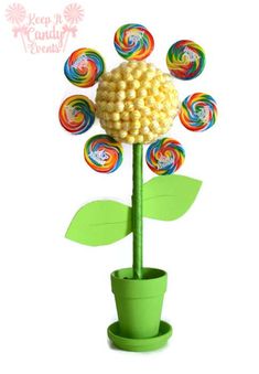 a flower made out of lollipops sitting in a pot with leaves on it