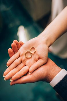 two people holding out their hands with wedding rings on them