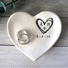 a heart shaped dish with two wedding rings on it and a ring holder in the shape of a heart