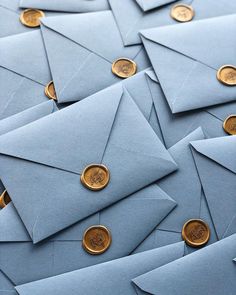 a pile of blue envelopes with gold buttons on them and some coins in the middle