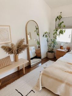 a bedroom with a bed, mirror and plants