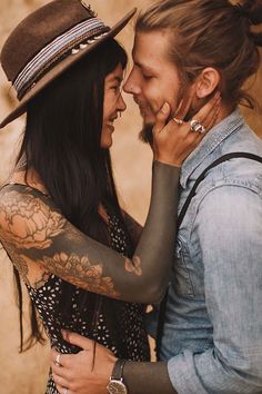 a man and woman embracing each other with tattoos on their arms