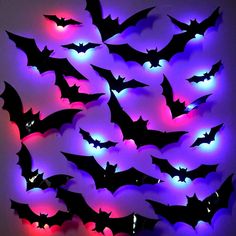 a bunch of bats that are lit up in purple and red lights on the wall