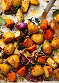 roasted potatoes and onions with herbs on a baking sheet