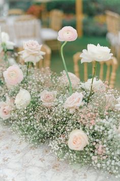 flowers and baby's breath are arranged in vases on a table at a wedding