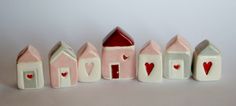 small houses with hearts painted on them are lined up against a white background and one has a red heart in the center