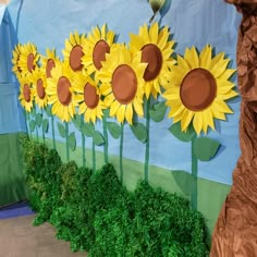 a wall with sunflowers painted on it and grass growing in the ground below