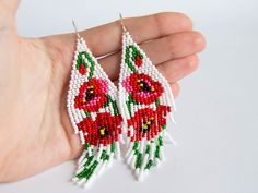 a pair of beaded earrings with red flowers on them