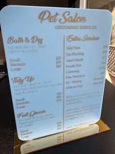 a menu for a pet grooming service on a gold and white stand up sign