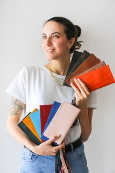 a woman holding several different colored folders in her hands