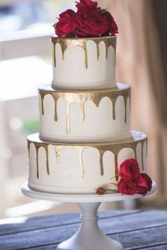 a three tiered cake with red roses on top