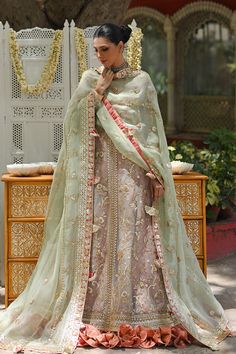 A tulle peshwas, featuring zardoze and resham embroidery, is paired with a salmon pink brocade lehnga and choli. Paired with a mint green organza dupatta accentuated with gota details and tassels. Raw Silk Dupatta With Dabka For Reception, Jamawar Dupatta With Dabka For Reception, Reception Dupatta With Dabka On Jamawar, Reception Traditional Wear With Dabka In Organza, Traditional Wear For Reception With Dabka In Organza, Organza Sharara With Dabka For Reception, Floor-length Raw Silk Lehenga With Dabka Detail, Floor-length Raw Silk Lehenga With Dabka, Traditional Organza Lehenga With Dabka Detailing