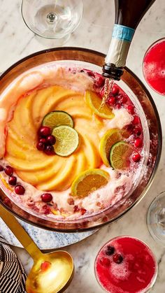 a bowl filled with fruit and garnish next to wine glasses