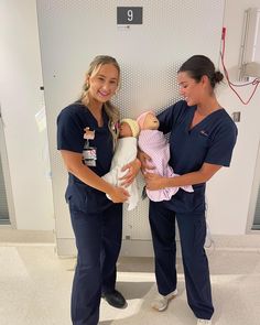 two women in scrubs holding a baby