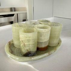 a plate with four glasses on it sitting on a counter top next to a stove