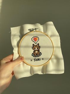 someone is holding up a cross stitch project