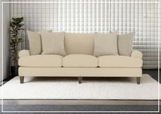 a white couch sitting on top of a rug in front of a wall with vertical blinds