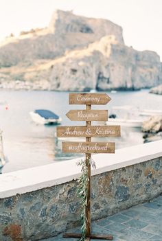 a wooden sign sitting on top of a stone wall