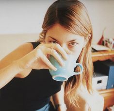 a woman drinking from a blue coffee mug